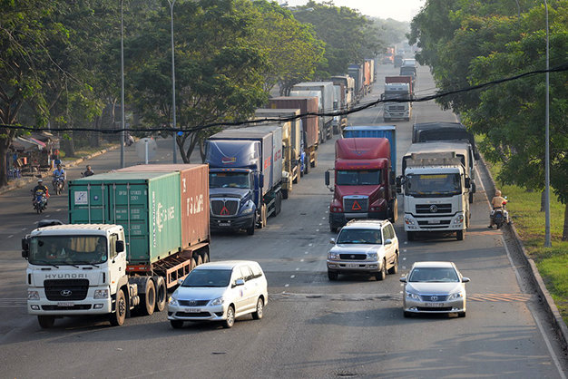 Do bị cấm nên hàng chục chiếc xe tải và container đậu kéo dài trên đường Nguyễn Văn Linh chờ hết giờ cấm để lưu thông khiến xe cộ khu vực này thường xuyên bị ùn ứ - Ảnh: Hữu Khoa