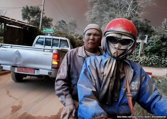 Residents with faces covered in ash ride on a motorcycle as Mount Sinabung volcano erupts, in Sukandebi village in Karo Regency, Indonesias North Sumatra province, June 13, 2015