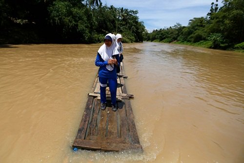Các học sinh phải đi học bằng một chiếc bè tre tạm bợ để vượt sông ở làng Cilangkap, Indonesia