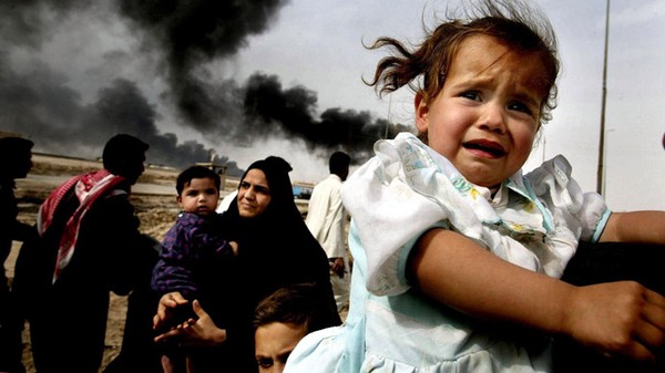 
Một bé gái khóc thét, ánh mắt đầy hoảng sợ đang chạy trốn khỏi bom rơi đạn nổ ngay phía sau em.
