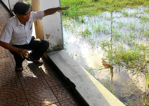 
 Mặt sân của trường ngập đầy nước do địa tầng lún sụt, dãy lan can bê tông hạ thấp gần sát mặt sân. Ảnh: Ngọc Văn
