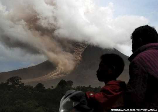 Residents sit on their motorcycle as they watch an eruption at Mount Sinabung, in Namanteran village in Karo Regency, Indonesias North Sumatra province, June 14, 2015