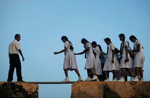 
Nữ sinh phải đi qua một thanh gỗ được bắc tạm trên bức tường từ thế kỷ thứ 16 ở Galle Fort ở Sri Lanka

