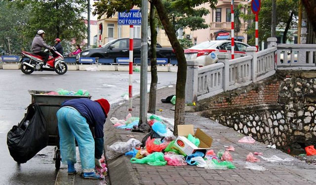 Những công nhân phải đi gom rác để cho vào xe rác sau khi người dân thả cá chép về trời