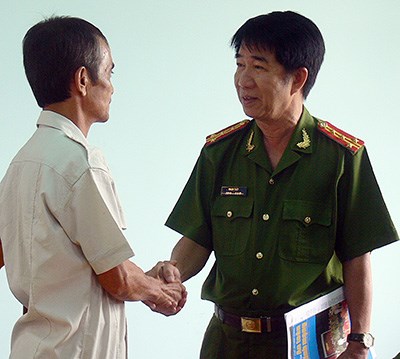 Đại tá Phạm Thật bắt tay chúc mừng công dân Huỳnh Văn Nén. Ảnh: PHƯƠNG NAM