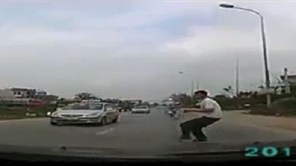 Người đàn ông bất ngờ chạy ra làn đường ô tô đang lưu thông và khom người lại (ảnh cắt từ clip)