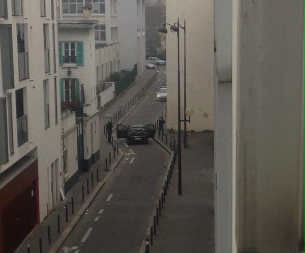 Bức ảnh đăng bởi phóng viên Elise Barthet của tờ Le Monde, cho thấy 2 kẻ tấn công đang chĩa súng vào một xe cảnh sát.