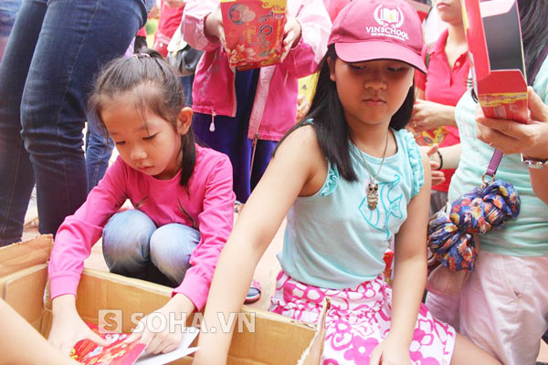 
Thành viên nhí Bùi Hải Hà My (đội mũ lưỡi trai) và cô bé Diệu Anh (6 tuổi) chăm chú đóng từng gói quà tặng các bạn học sinh

