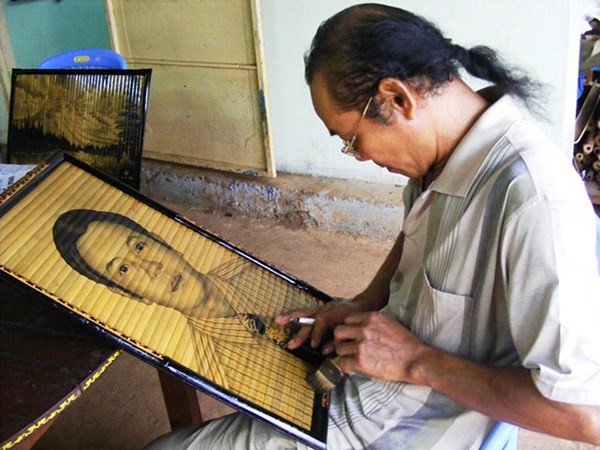 Vị họa sĩ này đang vẽ bức chân dung bằng chất liệu khói bếp trên khung tre. (Ảnh: Dân Việt)