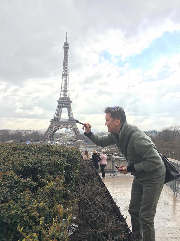 
Hình ảnh Mr Đàm dùng cây cọ sơn để tạo dáng hài hước bên công trình nổi tiếng của Pháp.
