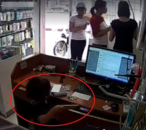 Cậu bé lục ngăn kéo lấy điện thoại, phía ngoài là hai người phụ nữ đang đánh lạc hướng nhân viên - ảnh cắt từ clip