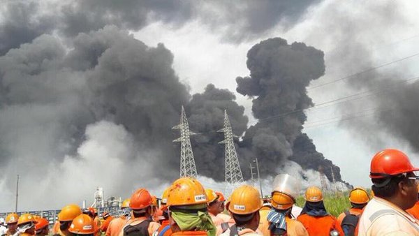Công nhân đứng nhìn khói đen bốc lên nghi ngút sau một vụ nổ lớn tại nhà máy lọc dầu Clorados 3 của tập đoàn Pemex tại thành phố thành phố Coatzacoalcos, bang Veracruz, Mexico.