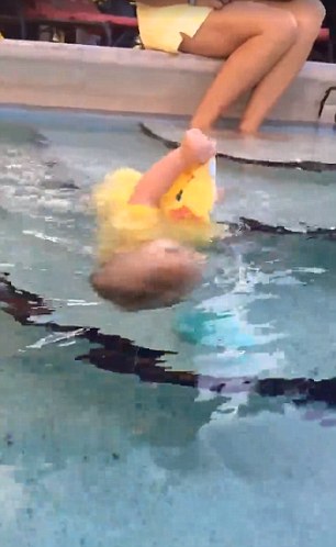 
Một bé gái mặc chiếc váy màu vàng đang cố với chiếc dép trôi trước mặt và ngã nhào xuống nước. 
