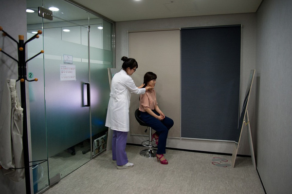 
Một bác sĩ đang kiểm tra gương mặt của bệnh nhân trước gương.
