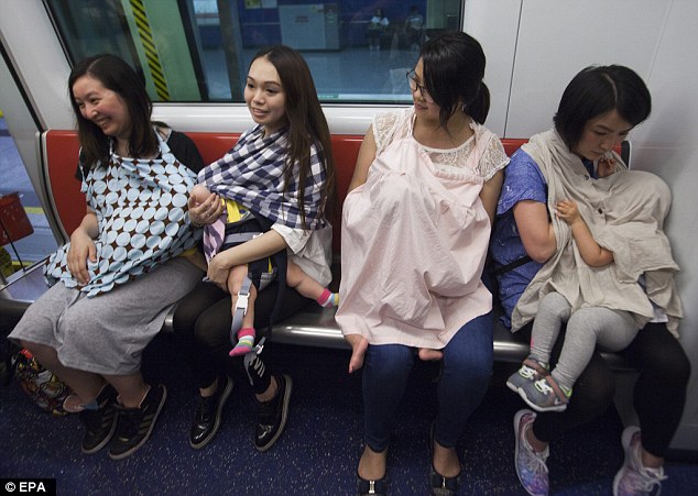 
Các mẹ ngồi và cho con bú trong 1 tấm khăn trùm bên ngoài tại trạm Tai Wai.
