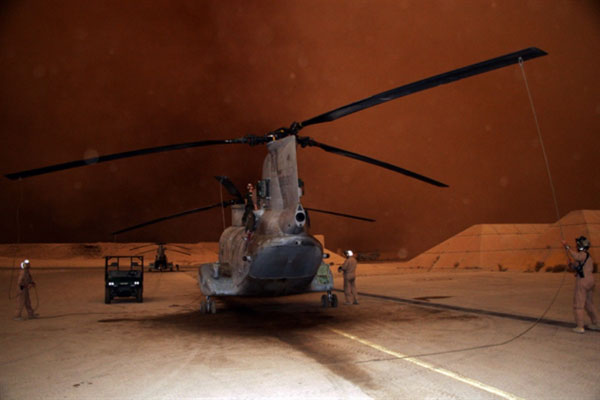 Các nhân viên kỹ thuật đang buộc dây giữ cánh quạt của trực thăng vận tải CH-47 khi một trận bão cát sắp quét qua.