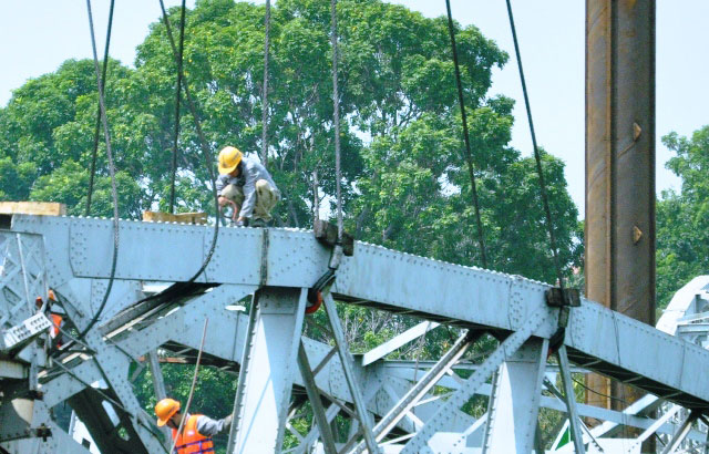 
Hai sà lan chứa 2 cẩu nổi xoay ngang, móc vào nhịp 2 đang treo để các công nhân tiếp tục cắt và hạ xuống nước.
