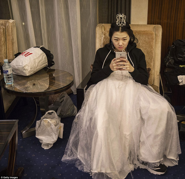 
Một cô gái trẻ ngồi sử dụng điện thoại sau khi đã hoàn thành màn khiêu vũ.
