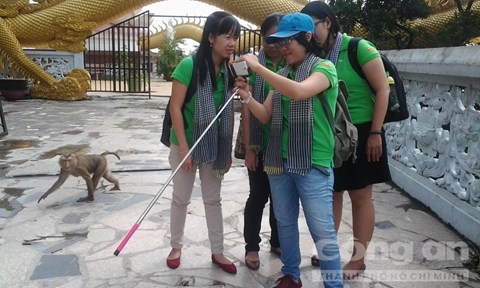 Một chú khỉ chạy tung tăng quanh một nhóm khách đang chụp hình tự sướng trên chùa. - Ảnh: Trí Trường