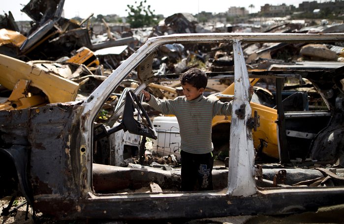 Cậu bé người Palestine chơi bên trong xác một chiếc ô tô phế liệu tại khu vực nghèo khó Khan Yunis, Dải Gaza.