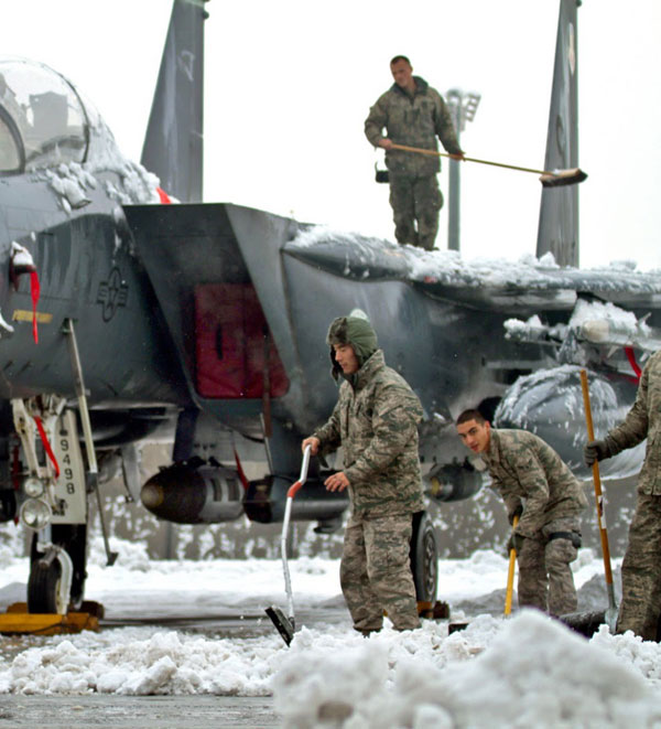 Các binh lính tranh thủ làm vệ sinh phần tuyết bám trên thân tiêm kích F-15 cũng như trên đường băng.