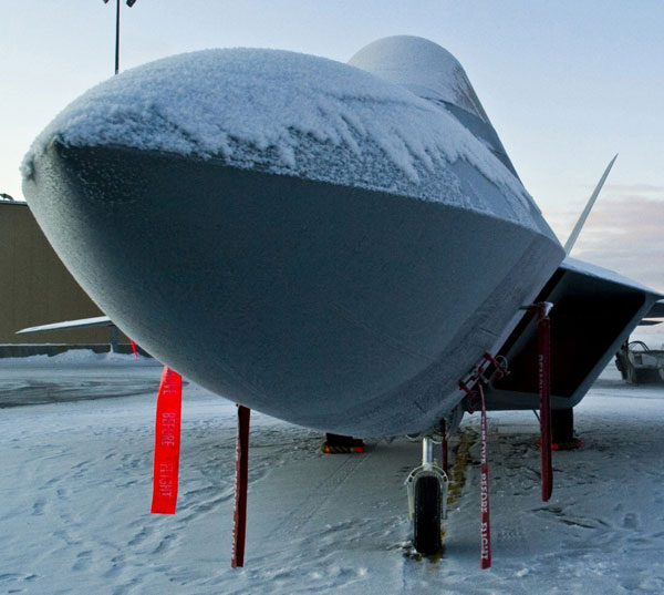 
Phần mũi và nắp buồng lái của tiêm kích tàng hình F-22 Raptor bị phủ một lớp tuyết dày, tuyết cũng phủ trắng xóa phần đường lăn cho máy bay.
