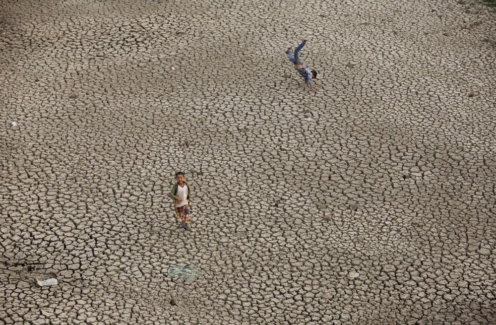 Trẻ em chơi đùa dưới đáy hồ cạn khô do hạn hán tại ngôi làng Chapagau ở Lalitpur, Nepal.