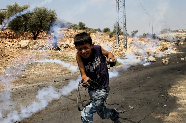 Một cậu bé người Palestine chạy khỏi đạn hơi cây của cảnh sát Israel trong cuộc đụng độ tại khu định cư của người Do Thái ở thành phố Nablus, Bờ Tây.