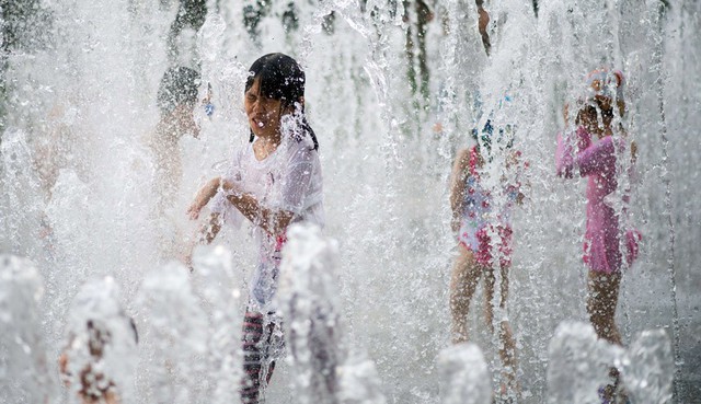 Các bé gái chơi trong đài phun nước khi nhiệt độ ngoài trời tăng cao tại Thượng Hải, Trung Quốc.