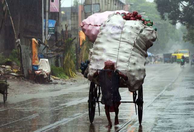 Một người đàn ông kéo xe chở hàng hóa dưới trời mưa ở thành phố Kolkata, Ấn Độ.