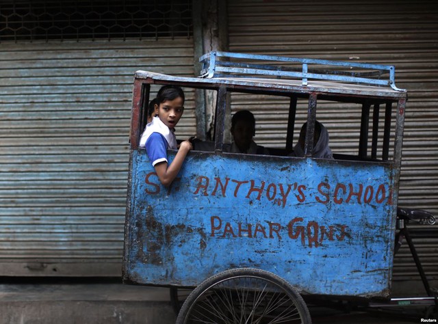 Các học sinh ngồi chờ trên xe kéo bên lề đường trong một buổi sáng ở Delhi, Ấn Độ.
