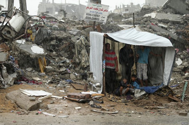 Những người Palestine trú mưa trong một túp lều tạm cạnh đống đổ nát của các ngôi nhà ở thành phố Gaza.