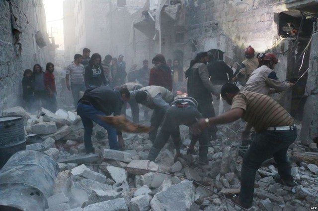 Nhân viên cứu hộ và người qua đường dọn dẹp đống đổ nát sau cuộc không kích của quân đội chính phủ nhằm vào thành phố Aleppo, Syria.