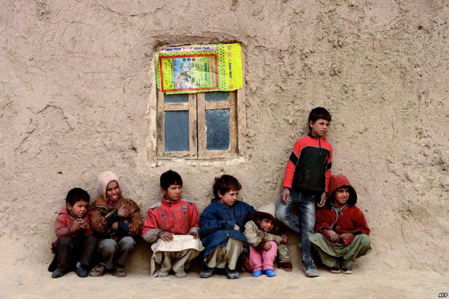 Trẻ em ngồi gần nhà của chúng ở Herat, Afghanistan. Vào mua đông, nhiều người dân ở miền Trung nước này đối mặt với tình trạng thiếu lương thực và chỗ ở.