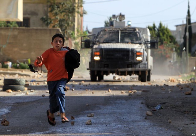 Cậu bé người Palestine chạy tìm nơi trú ẩn khi phương tiện quân sự Israel xịt hơi cay phía sau tại thị trấn Nablus, Bờ Tây.