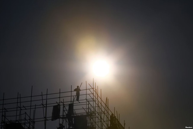 Người lao động làm việc trên đỉnh giàn giáo tại một công trường xây dựng ở Bắc Kinh, Trung Quốc.