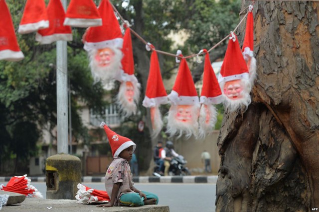 Cậu bé bán mũ và mặt nạ ông già Noel tại một ngã tư đường phố ở Bangalore, Ấn Độ.