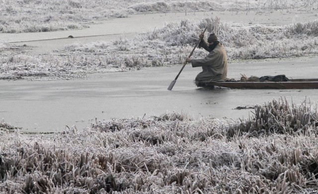 Người đàn ông chèo thuyền trên mặt hồ đóng băng vào buổi sáng lạnh ở Srinagar, Ấn Độ. 