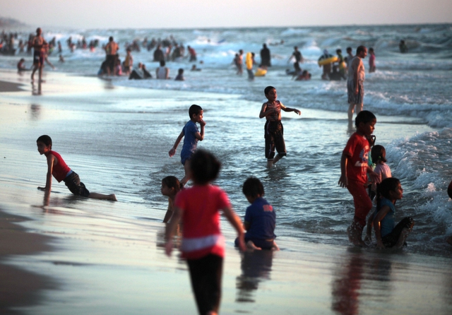 Trẻ em Palestine chơi đùa trên bãi biển để tránh nóng ở thành phố Gaza.