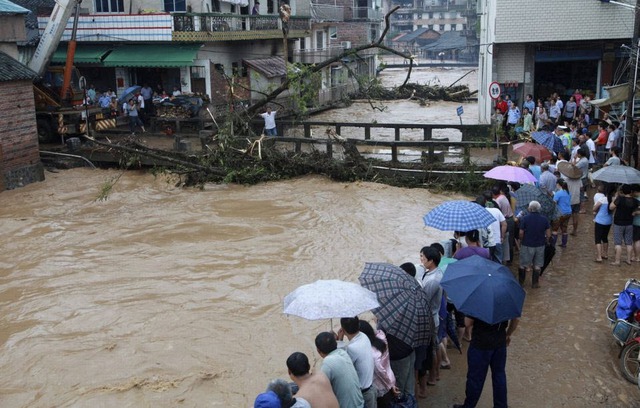 Người dân nhìn nước lũ cuốn trôi cây trên sông chảy qua thị trấn Shitang, tỉnh Quảng Tây, Trung Quốc.