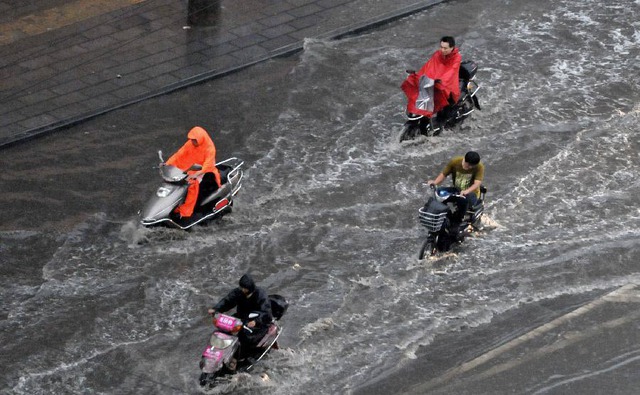 Người dân đi xe trên đường phố ngập nước ở thành phố Trịnh Châu, Trung Quốc.