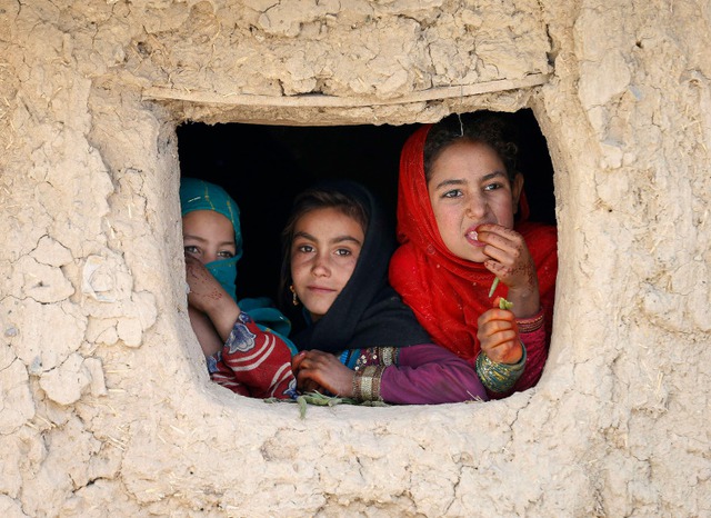 Các bé gái mất nhà cửa nhìn ra ngoài từ một ngôi nhà tạm ở Kabul, Afghanistan.