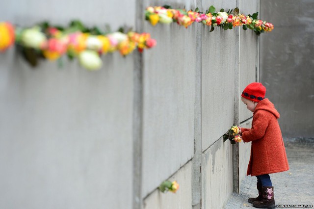Em bé đặt hoa tại một đọa bức tường Berlin được giữ lại trong dịp kỷ niệm 25 năm ngày bức tường Berlin sụp đổ.