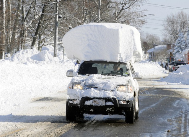 Chiếc xe ô tôi với khối tuyết khổng lồ trên nóc, đi trên đường phố ở Lancaster, New York, Mỹ.