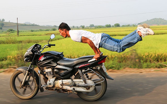 Người đàn ông biểu diễn tập yoga trên xe máy đang chạy với tốc độ cao ở Telangana, Ấn Độ.