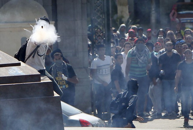 Những sinh viên ủng hộ phong trào Anh em Hồi giáo bắn pháo trong cuộc đụng độ với cảnh sát chống bạo động ngoài trường đại học Cairo, Ai Cập.