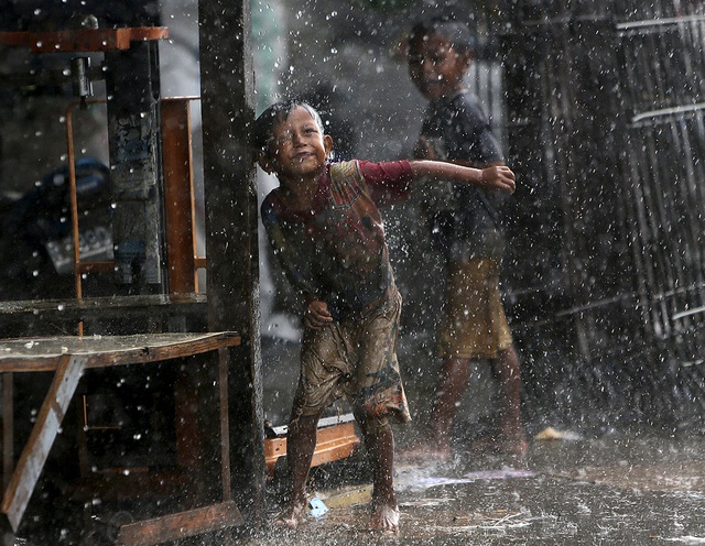 Trẻ em chơi dưới trời mưa lớn ở Jakarta, Indonesia.