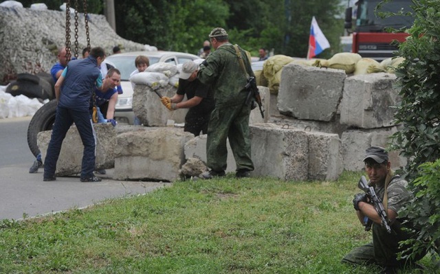 Một tay súng thân Nga đang canh gác trong lúc các đồng đội gia cố một điểm chốt ở ngoại ô Donetsk, Ukraine.