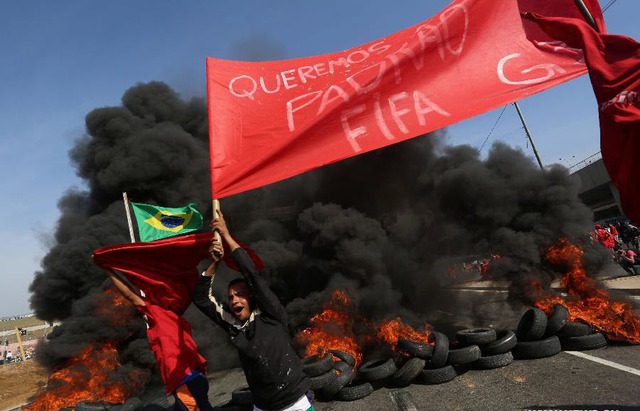 Người biểu tình mang khẩu hiệu, đốt lốp xe ô tô để phản đối chi phí cao của World Cup 2014 ở Sao Paulo, Brazil.