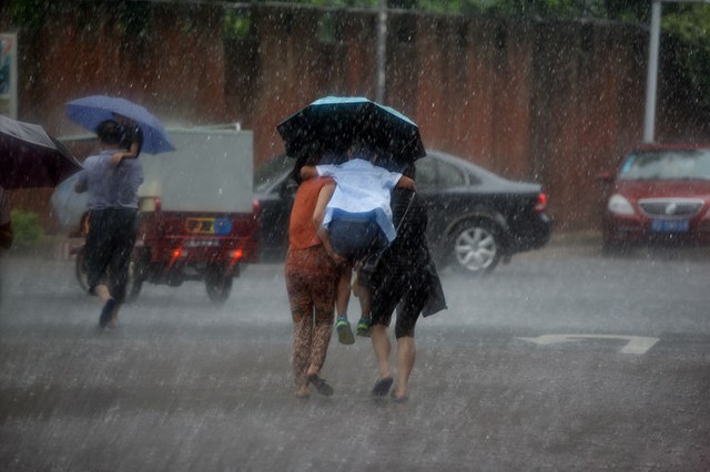 Khách du lịch chạy tránh mưa lớn tại thị trấn cổ ở Phượng Hoàng, tỉnh Hồ Nam, Trung Quốc.